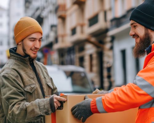 A reliable courier delivers his ordered products to a happy electrician working on a construction site.